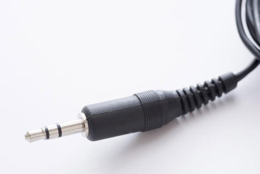 Audio jack 3.5 mm stereo plug with black cord in plastic body close-up on white background with copy space