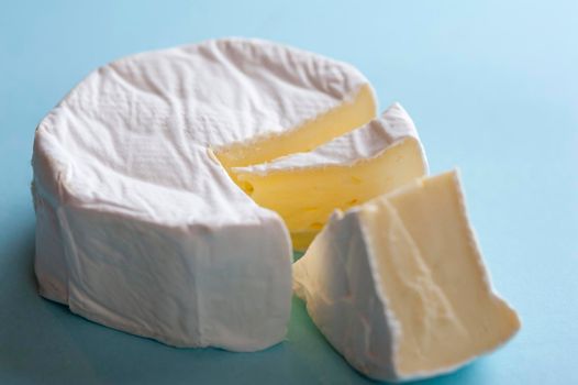 Round soft brie cheese with a wedge removed, closeup high angle view