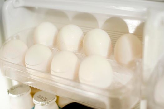 Tray of farm fresh white eggs in the the door of a fridge to be used as a healthy source of protein in cooking