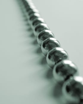 Unusual background with close up view of metal balls strung together against a light colored table