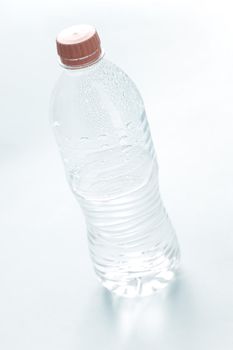 Pure water in an unlabeled closed plastic bottle, tilted high angle view on white