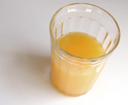 High angle view of a tall half drunk glass of fresh orange juice for a healthy breakfast rich in vitamin c on a white background with copyspace