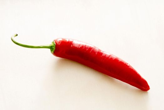 A close up of a vibrant, red chilli on a plain background with copy space.