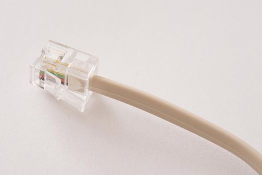 Clear plastic telephone plug or jack and cable over a white background with copy space in a communications concept