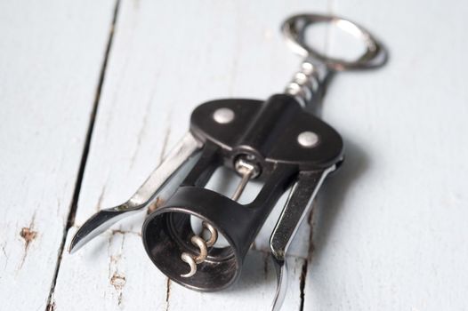 Corkscrew lever style bottle opener on rustic white wood with focus to the spiral tip of the screw