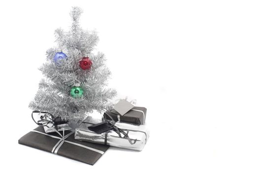 a small artificial silver tinsel christmas tree with presents inderneath