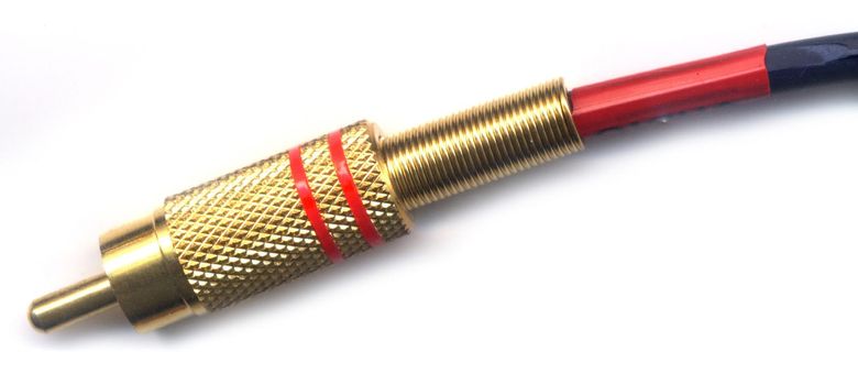 Metal RCA plug of golden color with red label stripes close-up isolated on white background