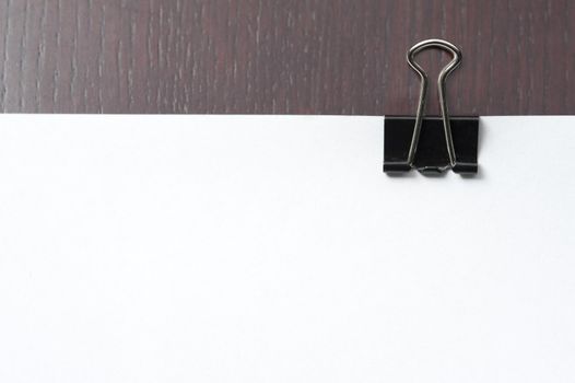 Documents and sheets of blank white paper clipped together with a bankers clip on the wooden surface of an office desk