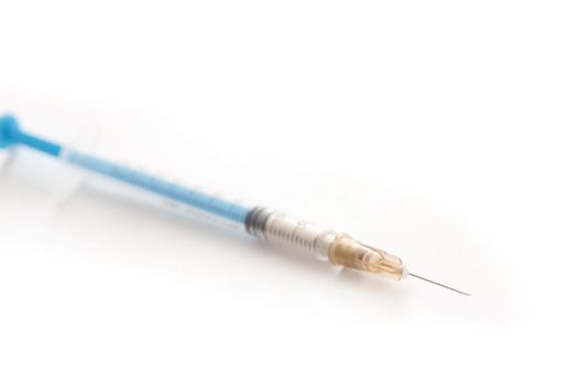 Small disposable plastic syringe or hypodermic with needle for administering medication subcutaneously in diseases such as diabetes, diagonally over white