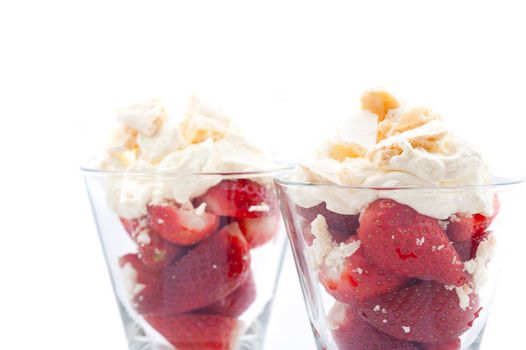 Close up view of ripe red luscious strawberries served with whipped cream in tall glasses isolated on white
