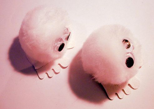 Pair of pink furry toys with large round eyes and four toes on feet from top view