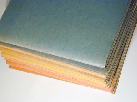 Pile of students school notebooks with blank covers viewed close up high angle on a white background in an education concept