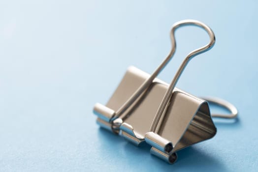 Close-up of bulldog clip against blue background