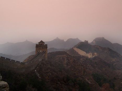 Atmospheric scenic landscape in colorful mist of the Great Wall of China and its lookout towers stretching away across mountain peaks in a travel concept