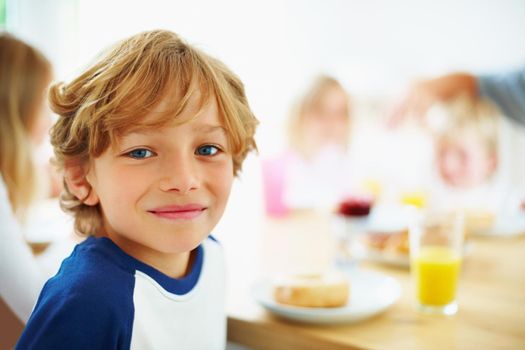Happy young boy with his family having breakfast. Closeup portrait of a happy young boy with his family having breakfast