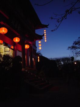 Door to a traditional Chinese house lit by red lanterns shining in the darkness of the night in a welcoming scene