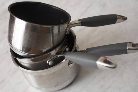 Stack of clean metal pans of assorted styles for cooking the food on a kitchen table