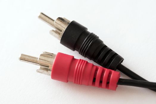 Stereo RCA phono connectors in rubber body of black and red colors, close-up on white background