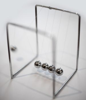 Newtons cradle executive desk toy with five suspended metal balls which transmit motion when one end ball is raised and released