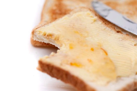 Slice of white buttered toast with a bite taken out of one corner, close up view