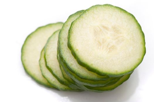 Stack of thin cucumber slices with focus to the top slice showing texture detail of the succulent flesh and pips