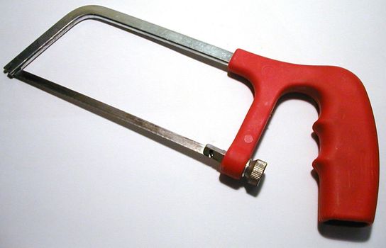 Junior hacksaw with fine-toothed saw and red plastic handle, close-up on gray