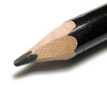 Sharpened black wooden pencil point in a close up macro view over white with shadow