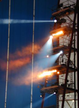 Tower supporting spotlights at a circus show arranged on various levels in assorted colors beaming down at night