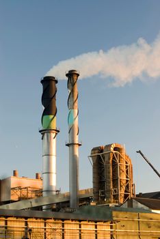 Industrial chimney at a factory or manufacturing plant emitting smoke into the air causing atmospheric pollution