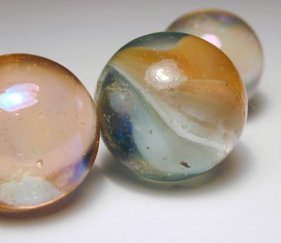 Close Up of Three Glass Marbles in Different Sizes on White Studio Background with Foreground Copy Space