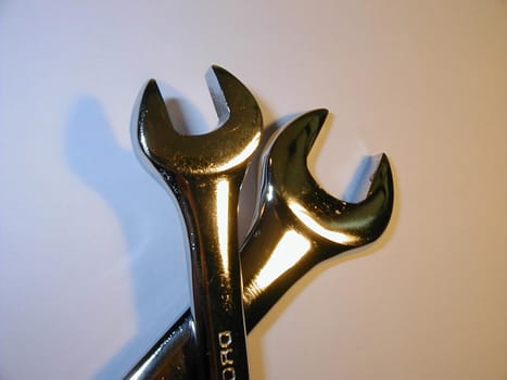 Two golden crossed spanners, useful tools for repairing and settings, high-angle close-up