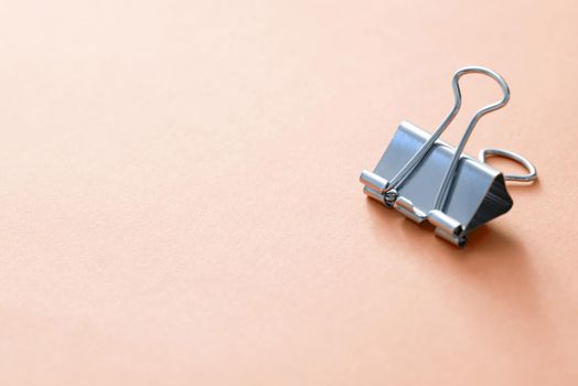 A single, metal office paper bull clip isolated on a plain background with copy space.