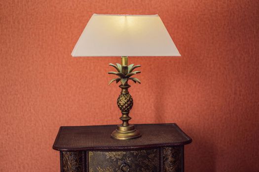 Bright eco light in the corner of a modern bedroom. New led technology meets traditional interior design. Lamp is creating cozy atmosphere in room. Wooden, glass table, blue curtains.