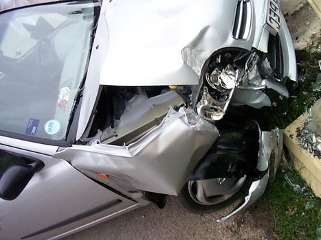 Crumpled car after an accident with front end damage and part of the bonnet missing exposing the engine, high angle view