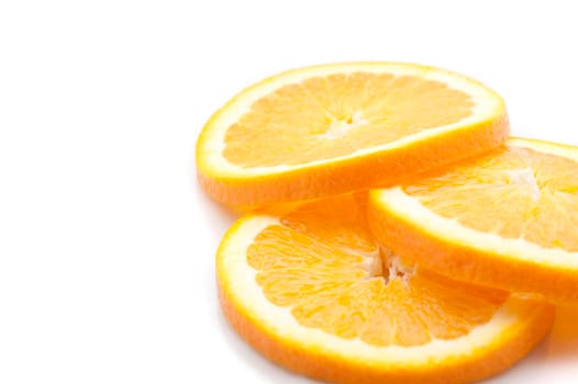Closeup view of three slices of thinly sliced fresh orange showing the segmented pulp and rind ready for use as a garnish lying on a white background with copyspace