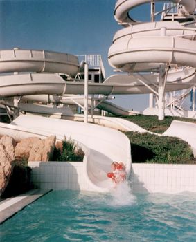 Person riding the slides at a water park entering the water of the pool below with a splash