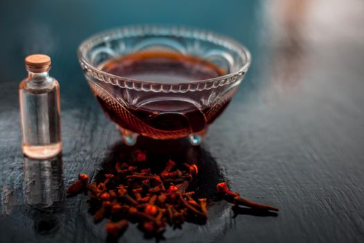 Clove face mask for prevention against acne and pimples on wooden surface in a glass bowl along with clove oil and some coconut oil.