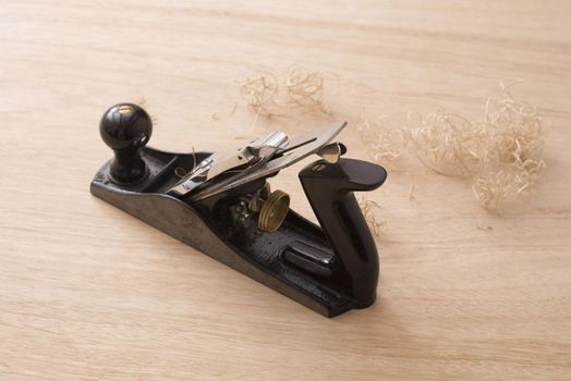 Carpenters plane tool and shavings on wooden surface viewed from high angle