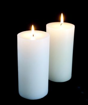 two plain white christmas candles on a black background