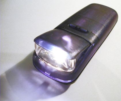 Close Up of Illuminated Purple Flashlight Torch with Lit Lamp on White Background