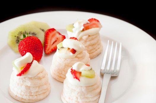 Serving of crisp meringue cones filled with whipped cream and fresh fruit for a healthy dessert