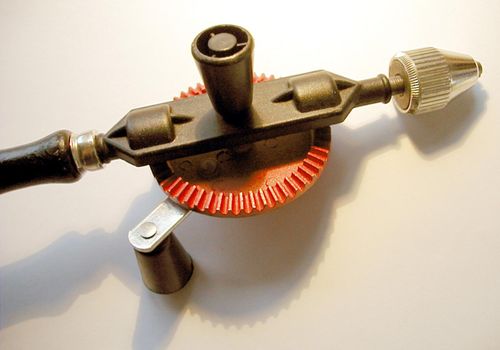 Close Up Detail of Old Fashioned Handheld Drill Angled on White Background