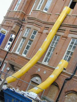 Renovation construction on an old red brick building with external chutes to dispose of building waste reaching down to a tip on the ground to