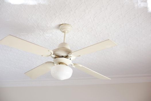 Retro ceiling fan with light fixture and four white blades for keeping cool in the summer heat