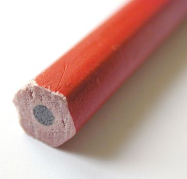 Back end of a red wooden pencil showing the graphite lead in a macro view with selective focus over white