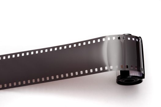 Open roll of exposed 35mm film unwound from the canister over a white background viewed from above with copy sapce