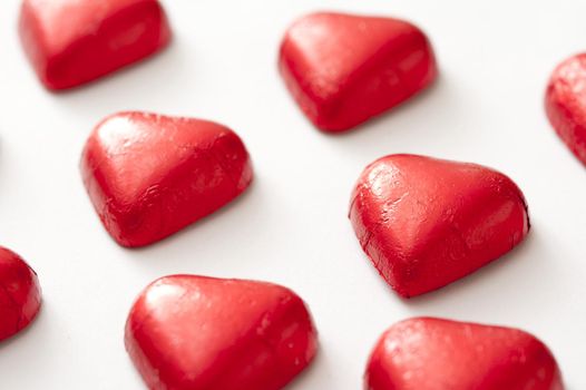 Foil wrapped red chocolate valentine hearts isolated on white background with copy space.