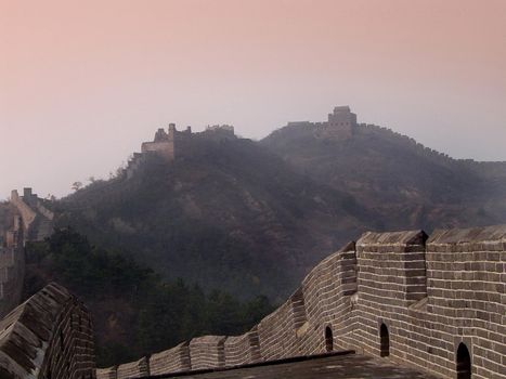 Tranquil Scenic of Historical Great Wall of China Through Fog Shrouded Mountains in Delicate Pink Lighting