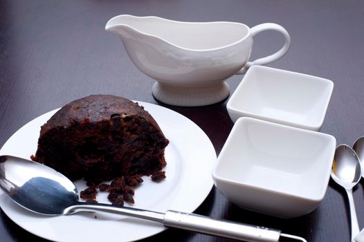 Spicy fruity traditional boiled Christmas pudding on a plate waiting to be served into two small dishes for a scrumptious seasonal dessert
