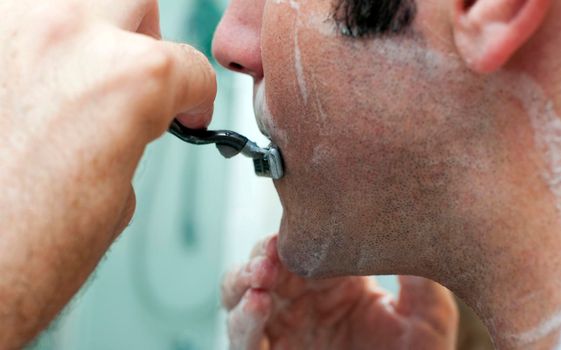 a man shaving with shaving foam and a blade safety razor